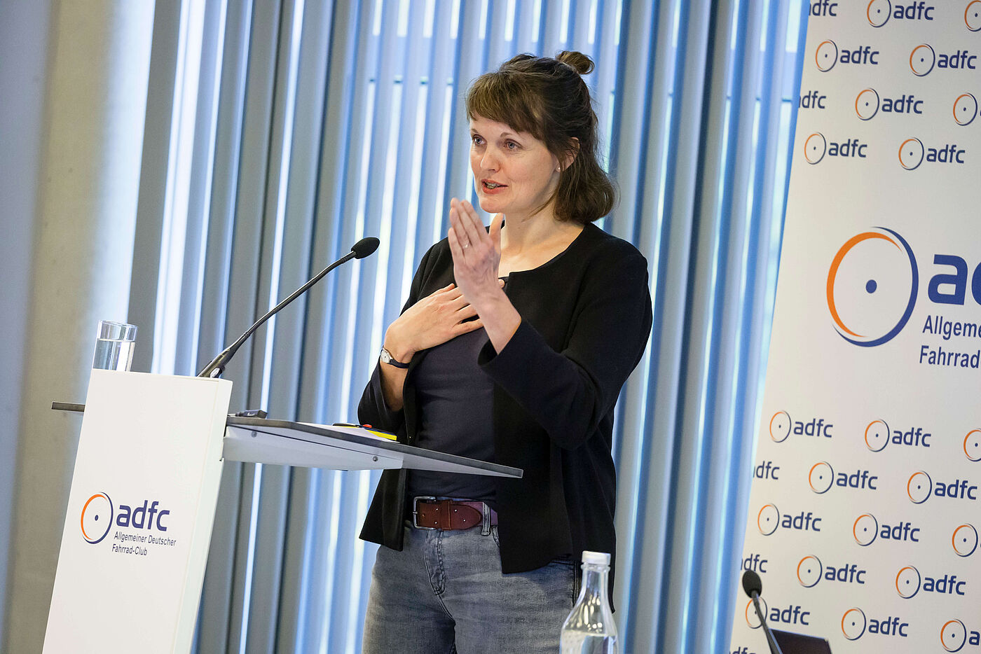 Swantje Michaelsen steht auf der Bühne am Pult mit Mikro.